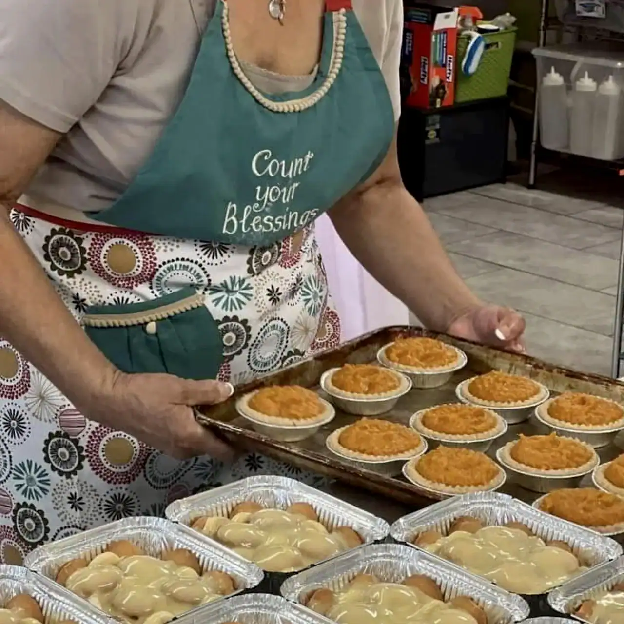 Homemade sweet potato pies and peach cobbler on baking trays.