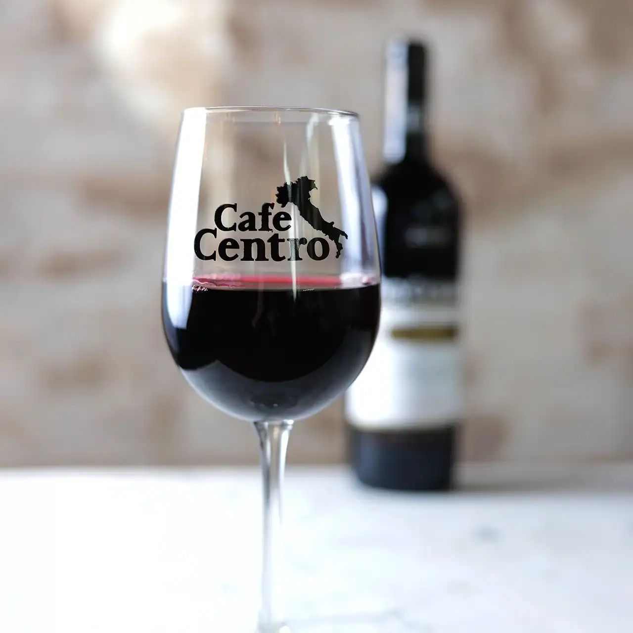Glass of red wine with Cafe Centro logo on it.