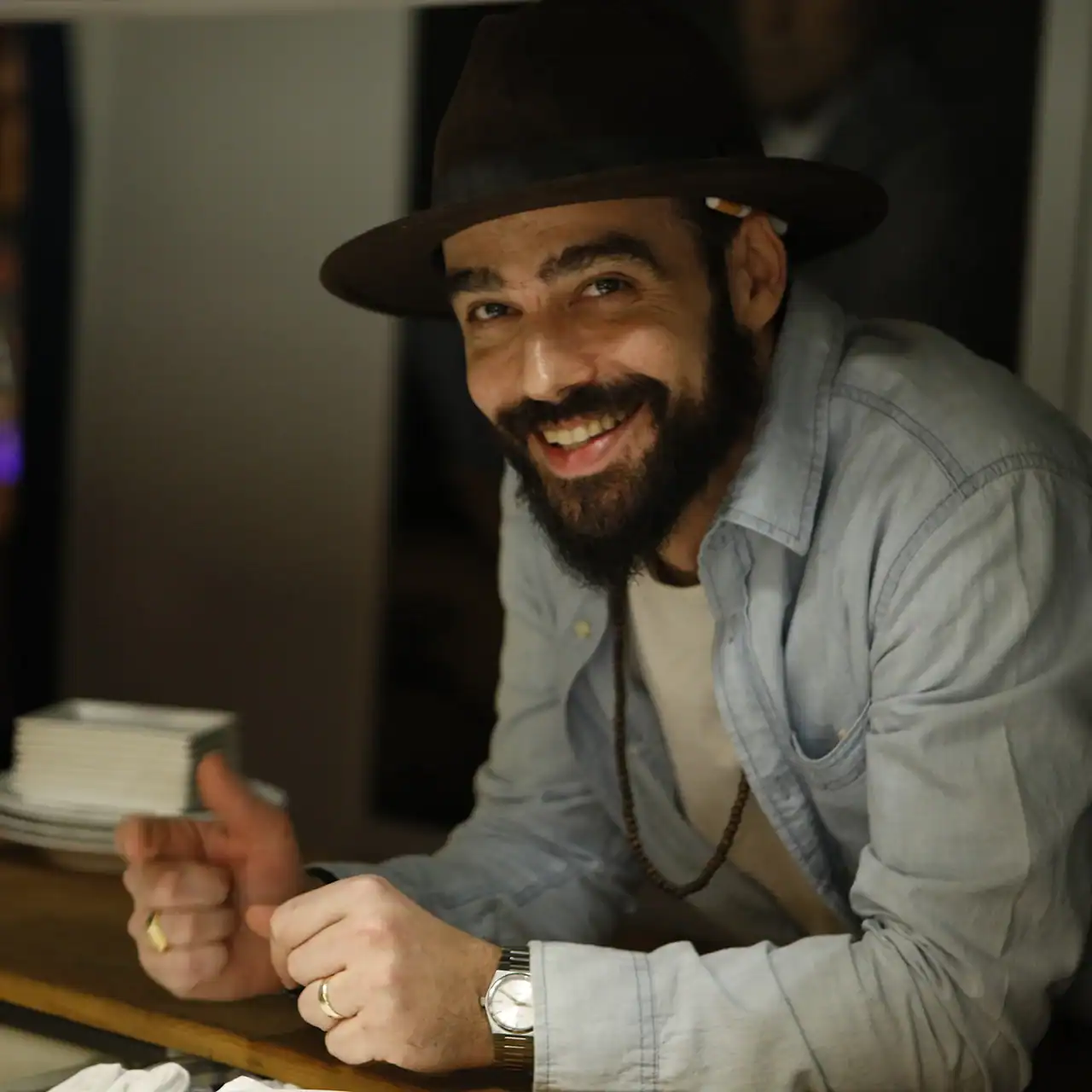 Man with a hat smiling, showing a friendly expression.
