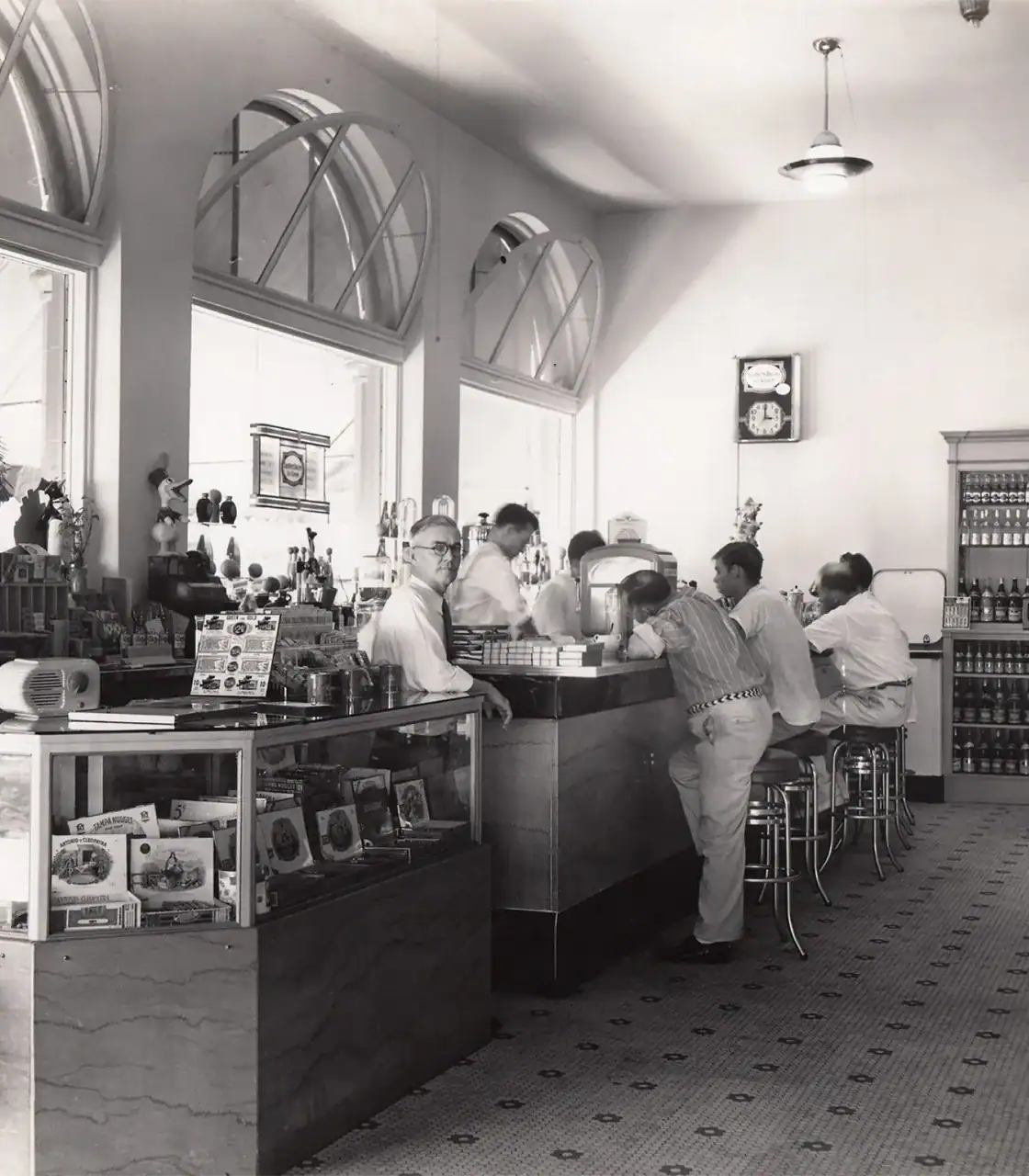 Counter with customers ordering drinks and food in a classic café setting.