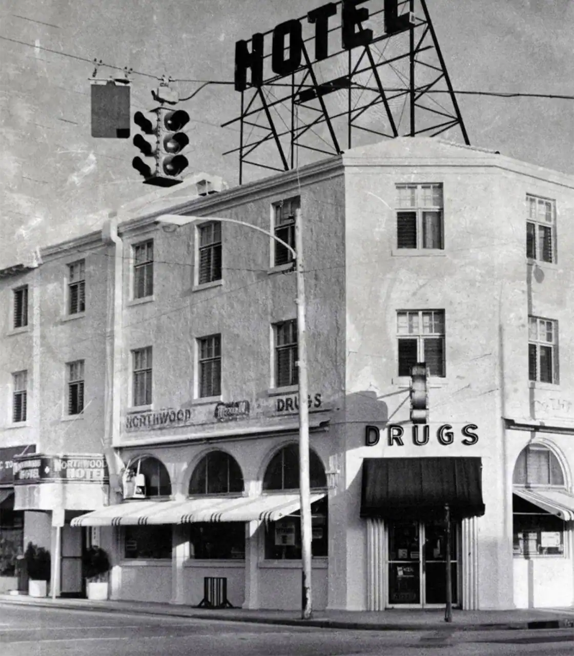 Traffic light and hotel building with drugstore sign in black and white.