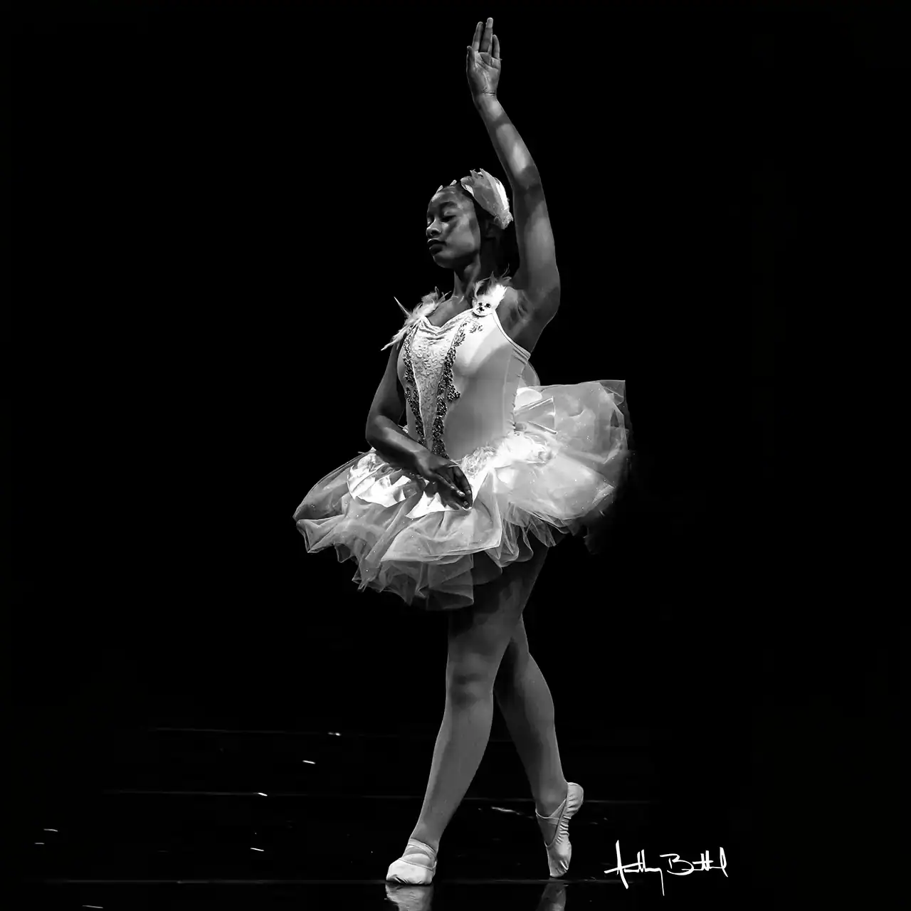 Ballet dancer in tutu with one arm raised during a performance on stage.