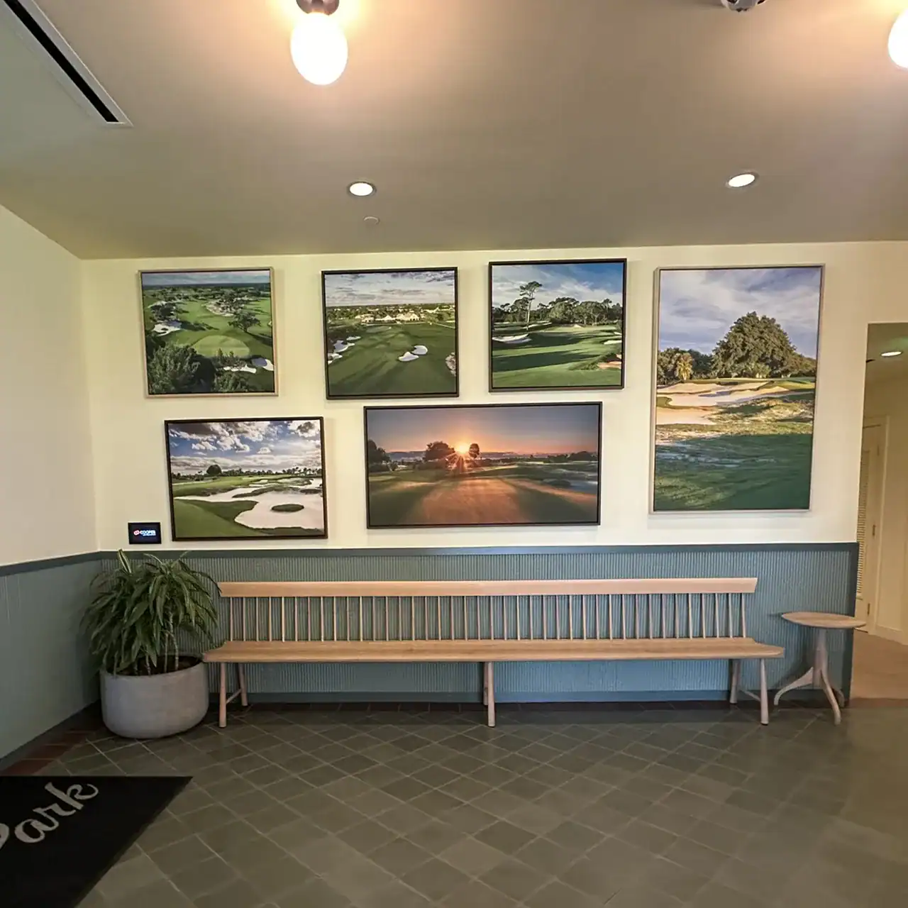 Indoor golf course artwork with framed photos of a golf course and sunset view.