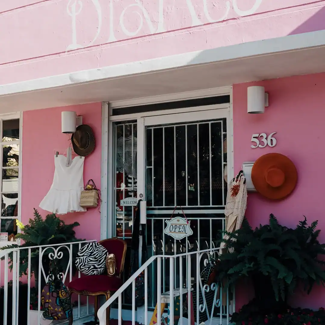 Boutique storefront with pink walls, hats, and decorative plants.