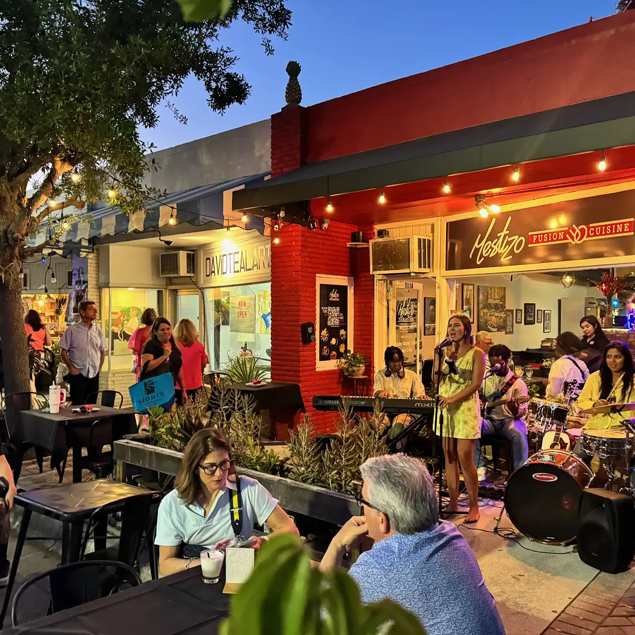 Live band playing music on an outdoor stage with audience enjoying the evening.