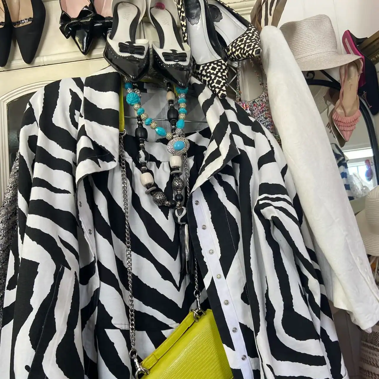 Zebra print shirt paired with layered necklaces, a yellow purse, and various shoes on display.
