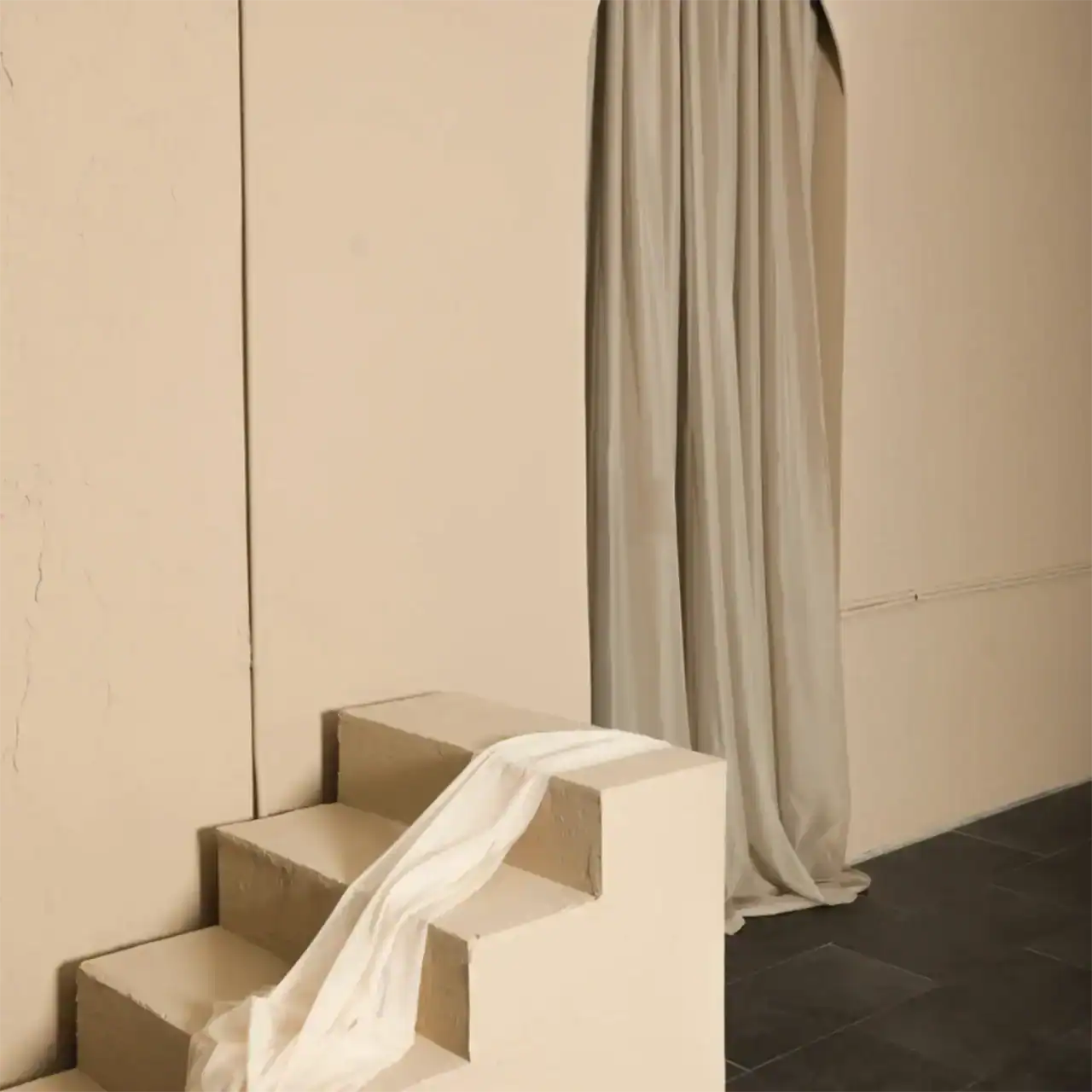 Staircase with a white cloth hanging over the steps, set against a plain wall.