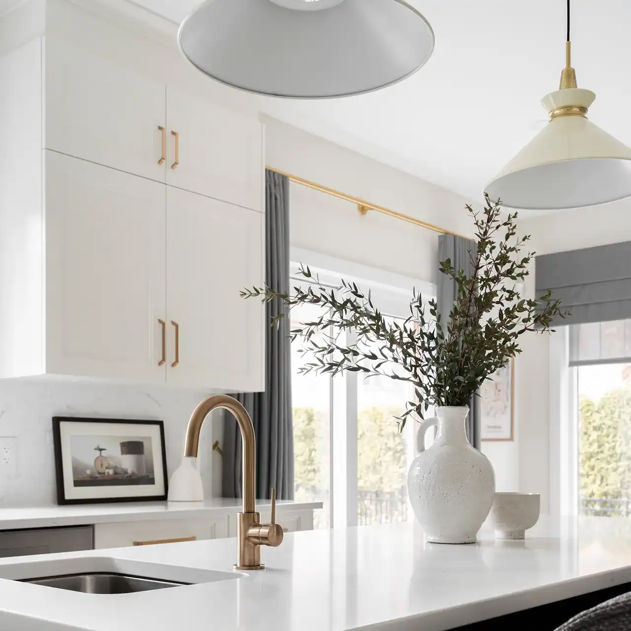 Kitchen sink with bronze faucet and decorative vase with greenery.