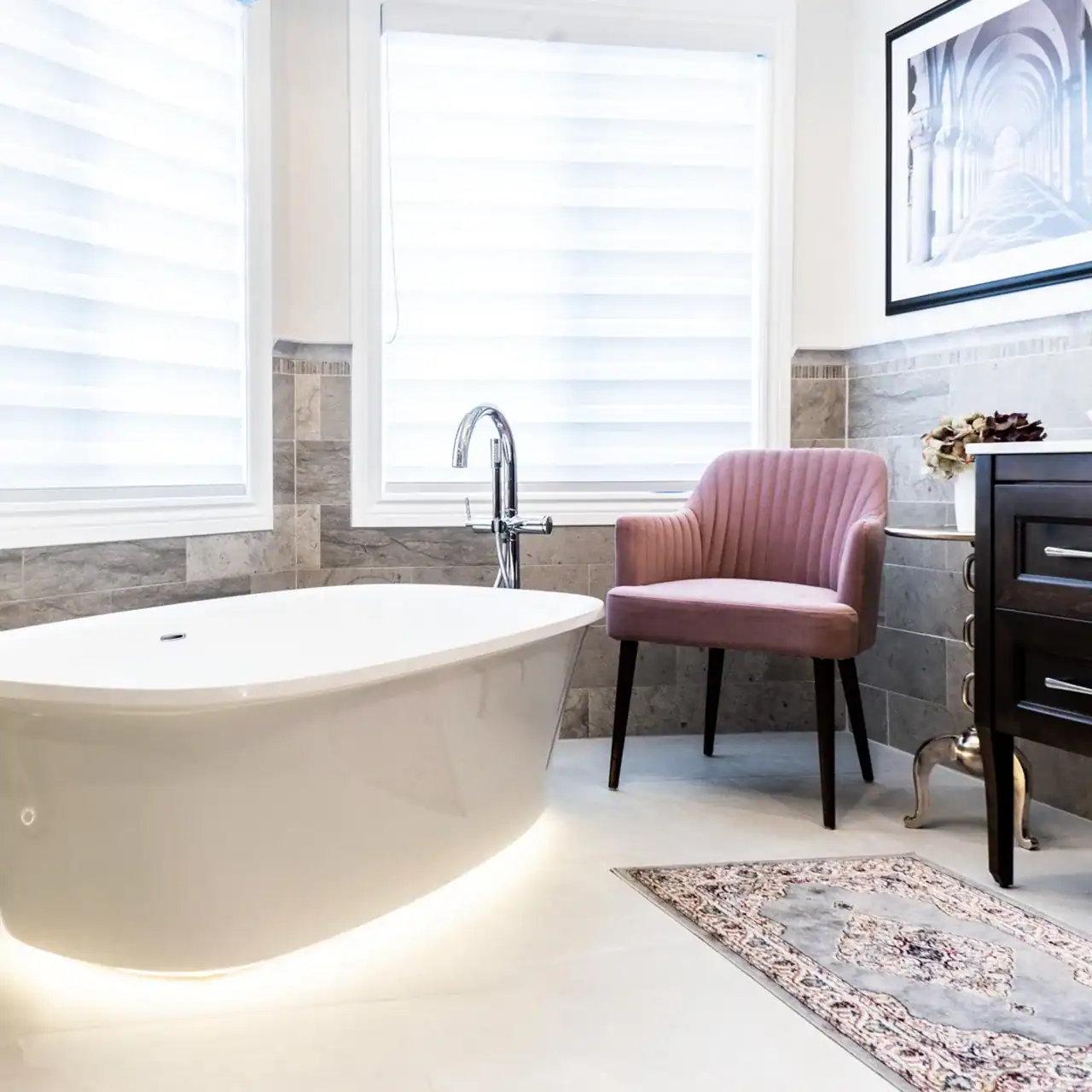 Freestanding bathtub and pink armchair in modern bathroom setting.