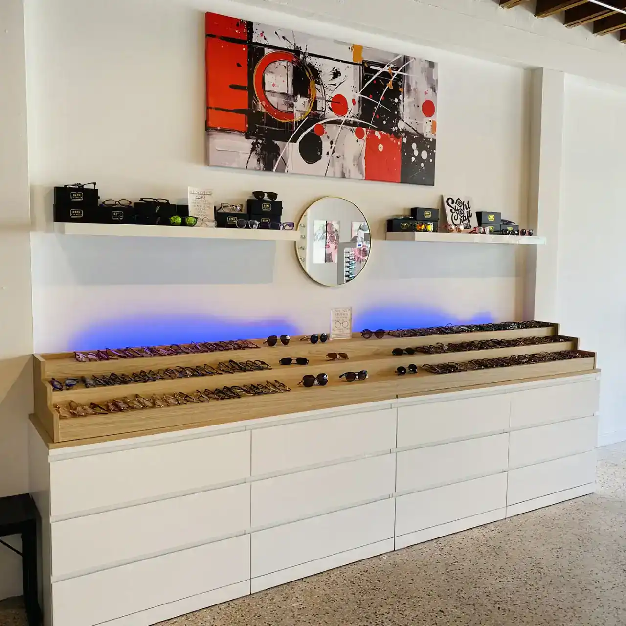 Eyewear display showcasing sunglasses on wooden shelves with modern decor.