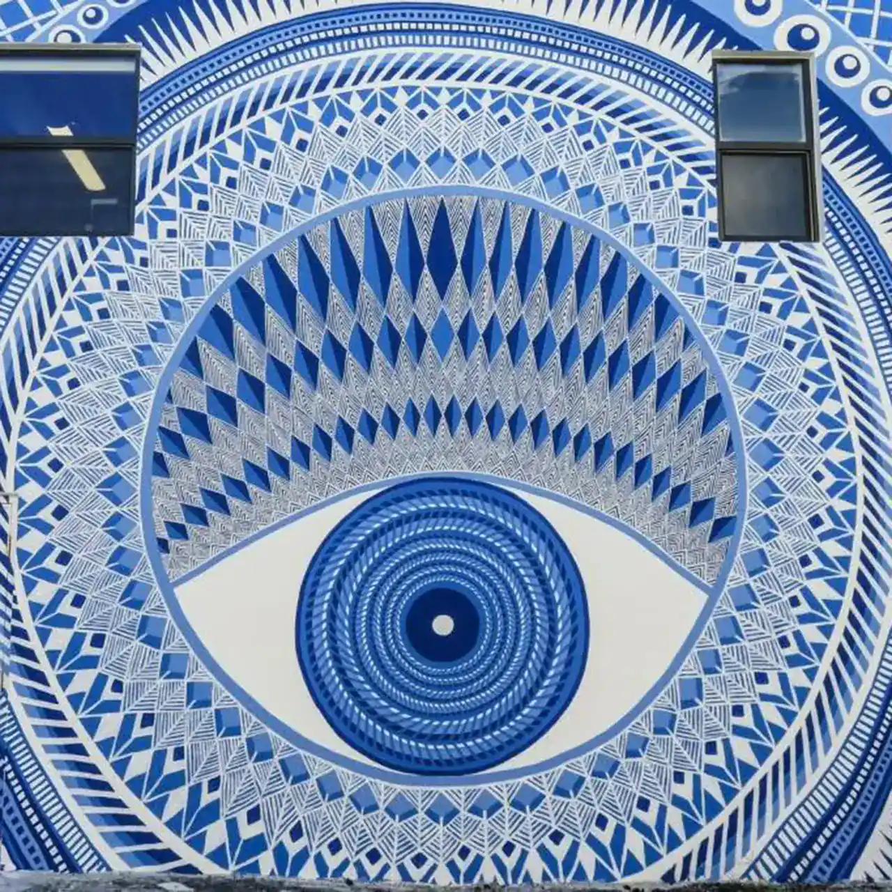 A large mural of a stylized, intricate blue and white eye dominates the wall.